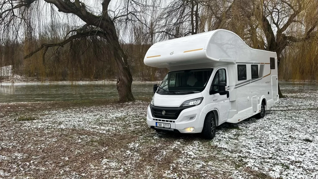 obytný vůz v přírodě před zamrzlým rybníkem